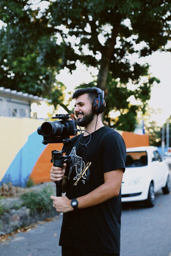 Photographer with camera and headphones filming outdoors in sunny Maricá, Brazil.
