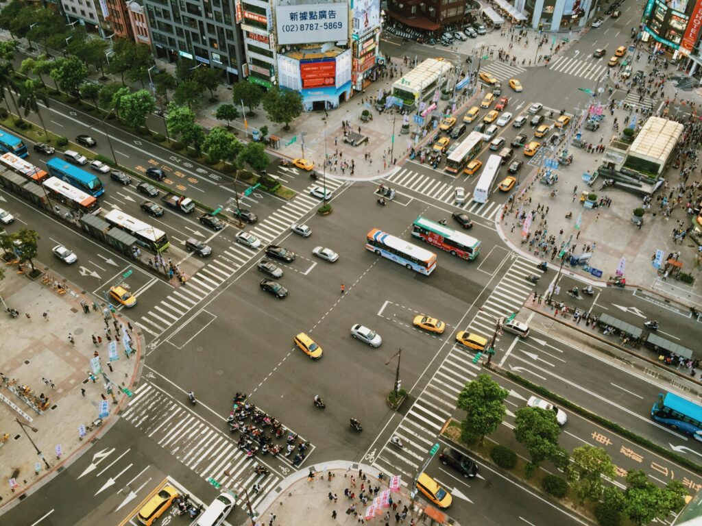 Aerial view showcasing busy city street life with traffic and pedestrians at an intersection.